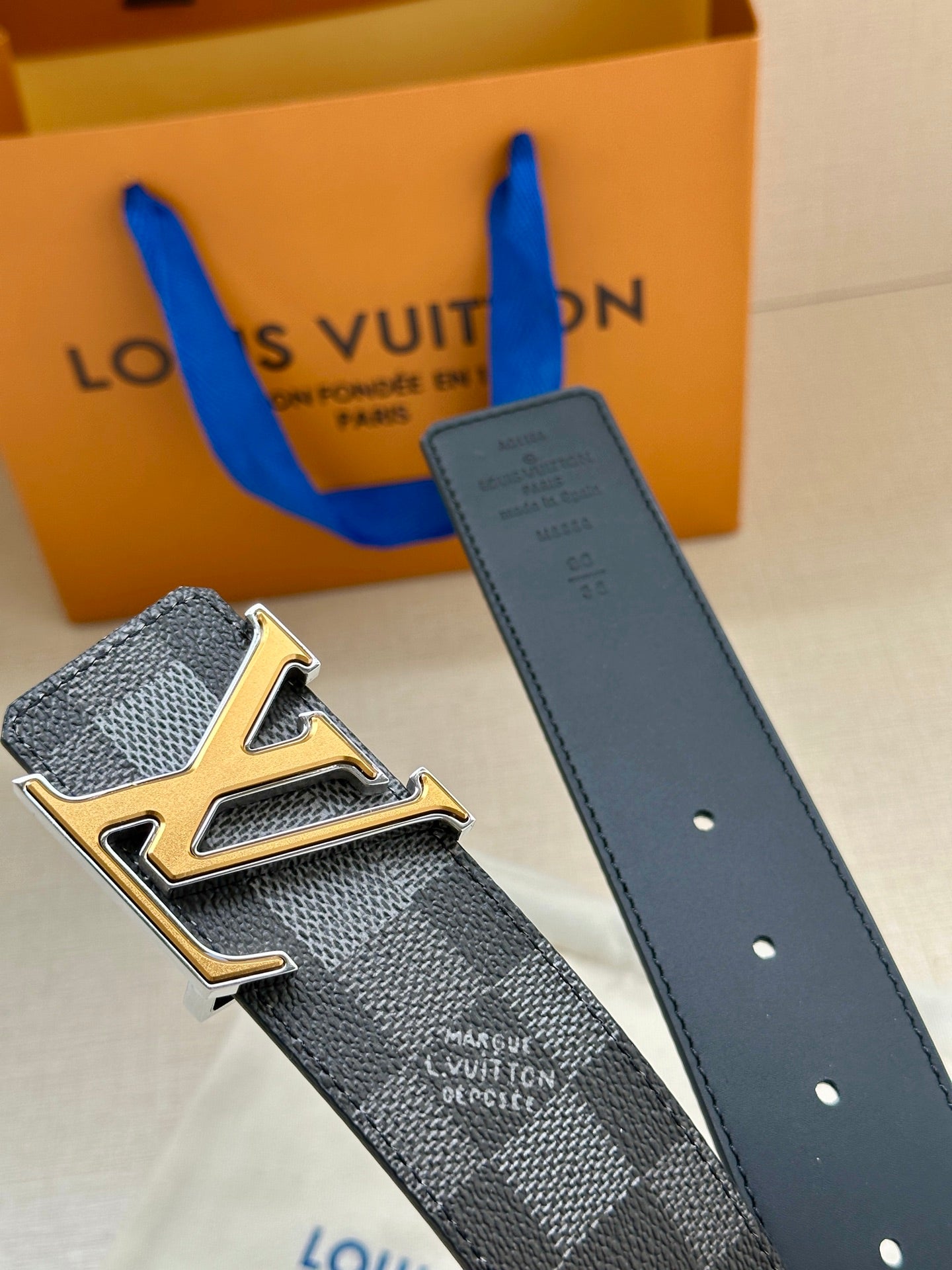 Louis Vuitton Damier belt and buckle close-up with dark gray strap
