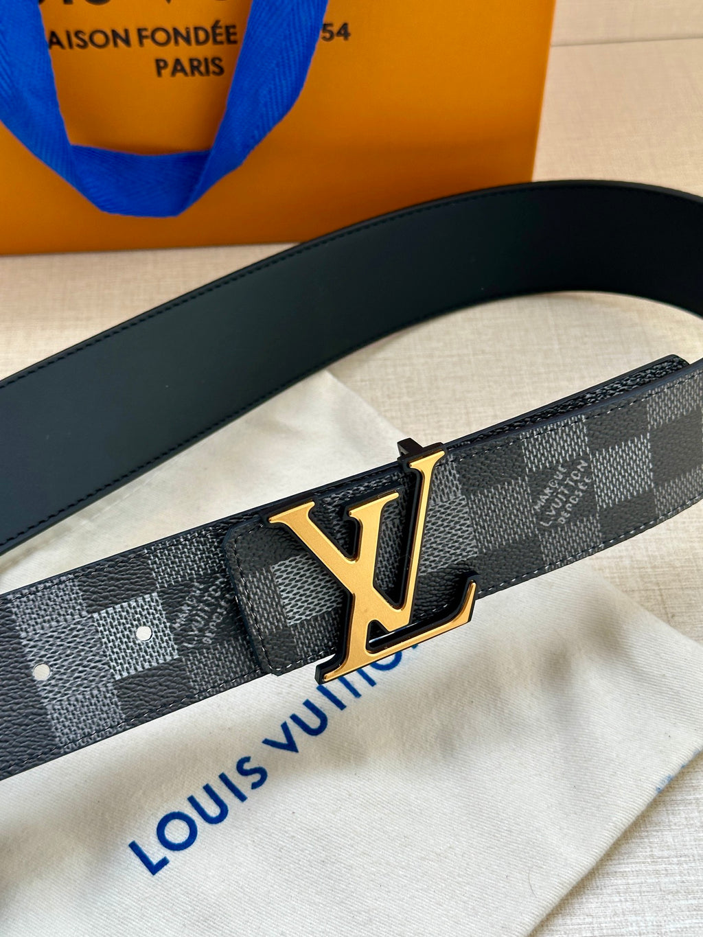 Louis Vuitton Damier belt close-up with gold LV buckle on dark strap