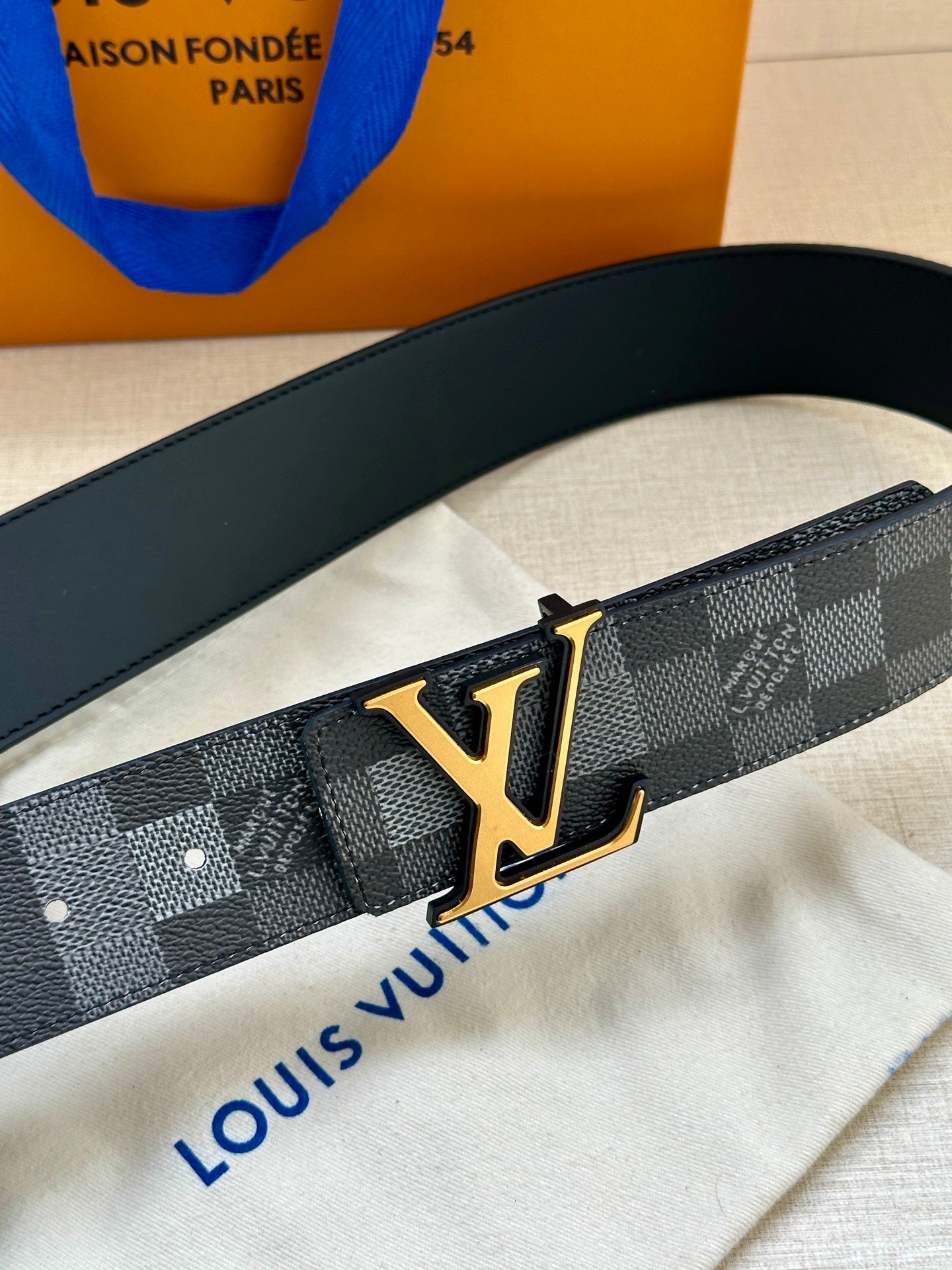 Louis Vuitton Damier belt close-up with gold LV buckle on dark strap
