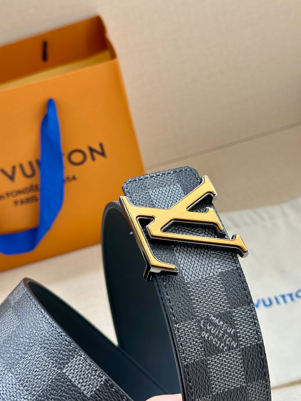 Louis Vuitton Damier patterned belt with gold LV buckle, dark gray strap