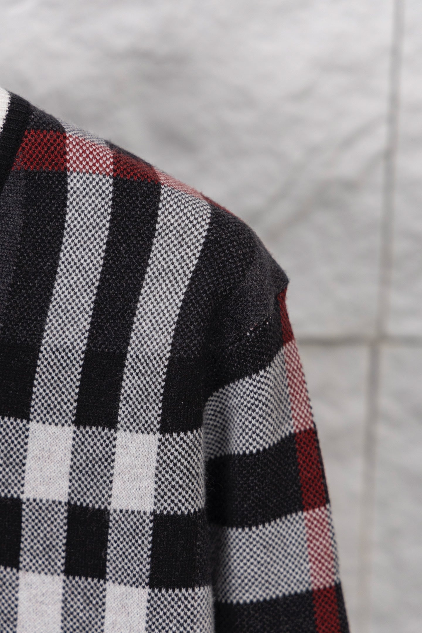 Plaid cardigan sleeve with bold white stripes over dark and red check pattern