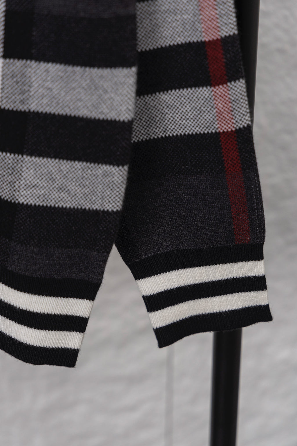 Plaid cardigan sleeve cuff with ribbed black-and-white stripes, dark with red check
