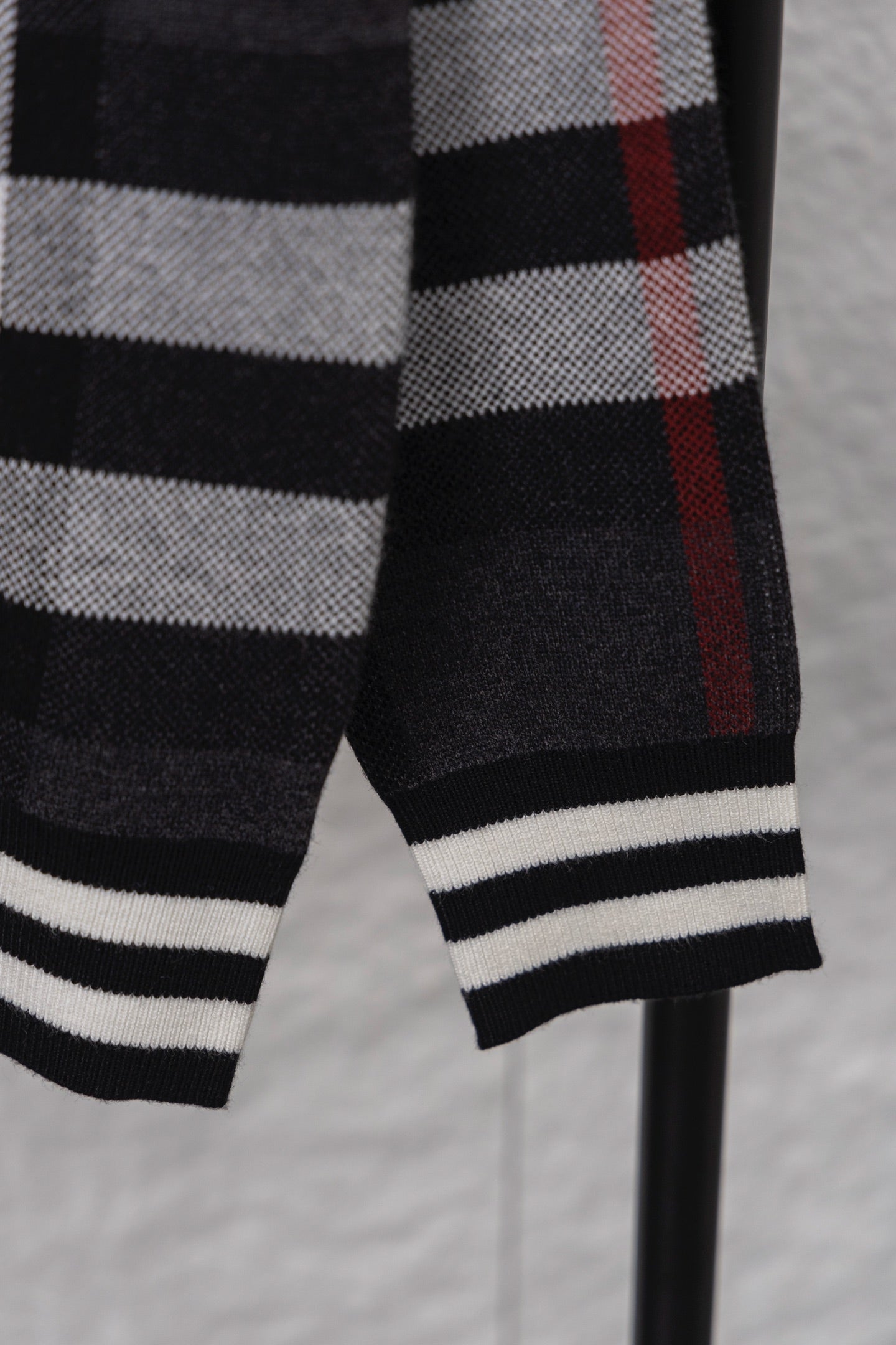Plaid cardigan sleeve cuff with ribbed black-and-white stripes, dark with red check