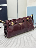 Prada burgundy leather shoulder bag with side straps, gold buckle details, and logo plaque