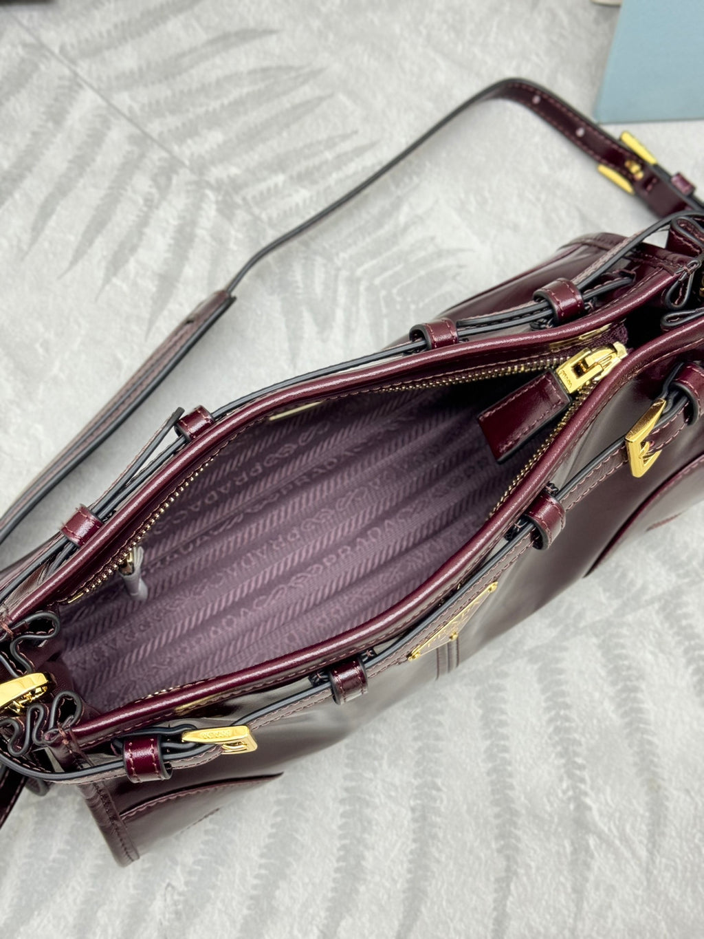 Prada burgundy leather bag open view with interior lining and gold hardware frame
