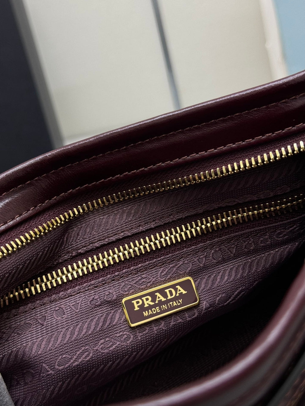 Prada burgundy leather bag interior close-up with zip closure and logo label on lining