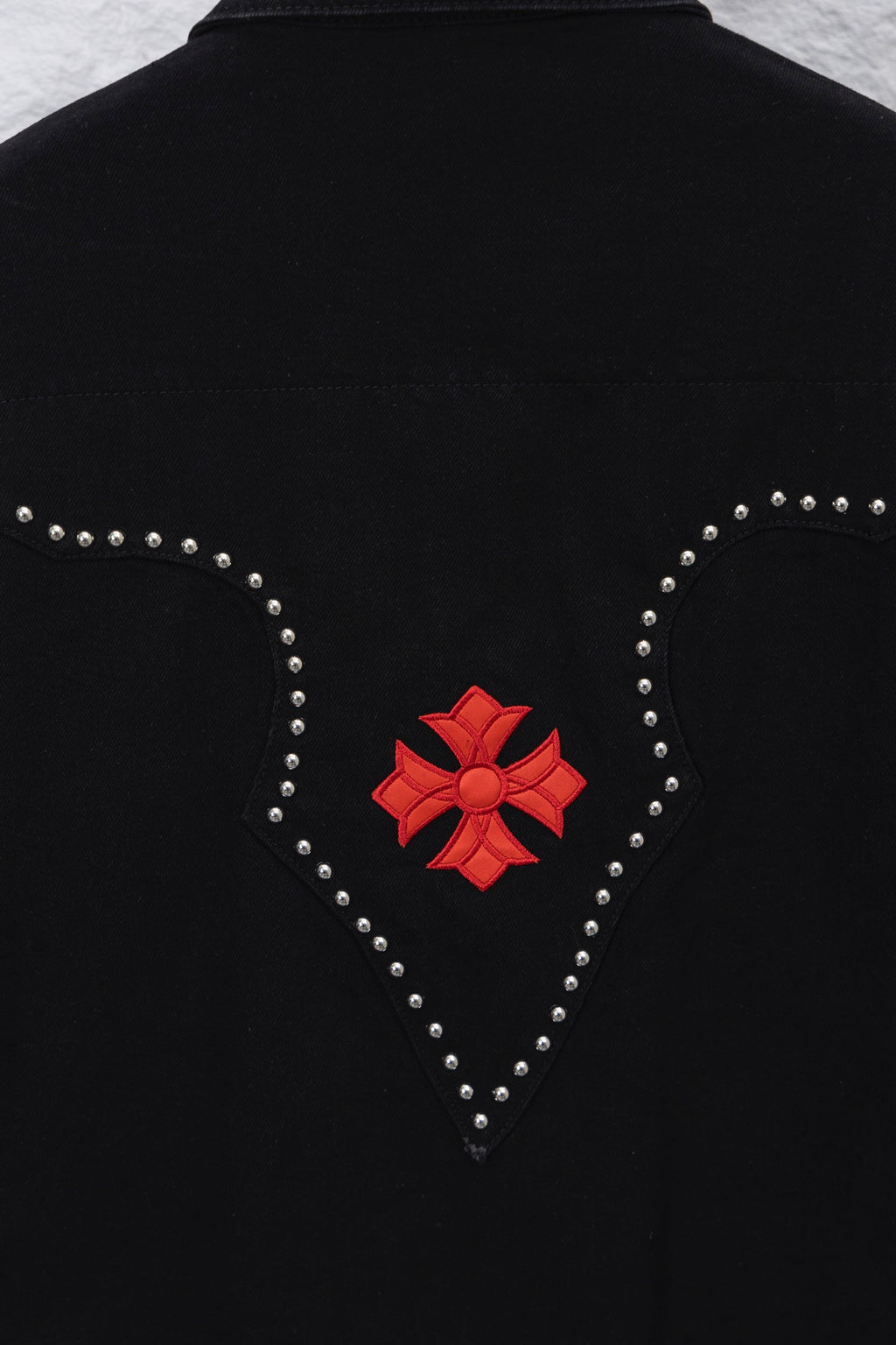 Black back of long-sleeve shirt with heart-shaped stud outline and red bow