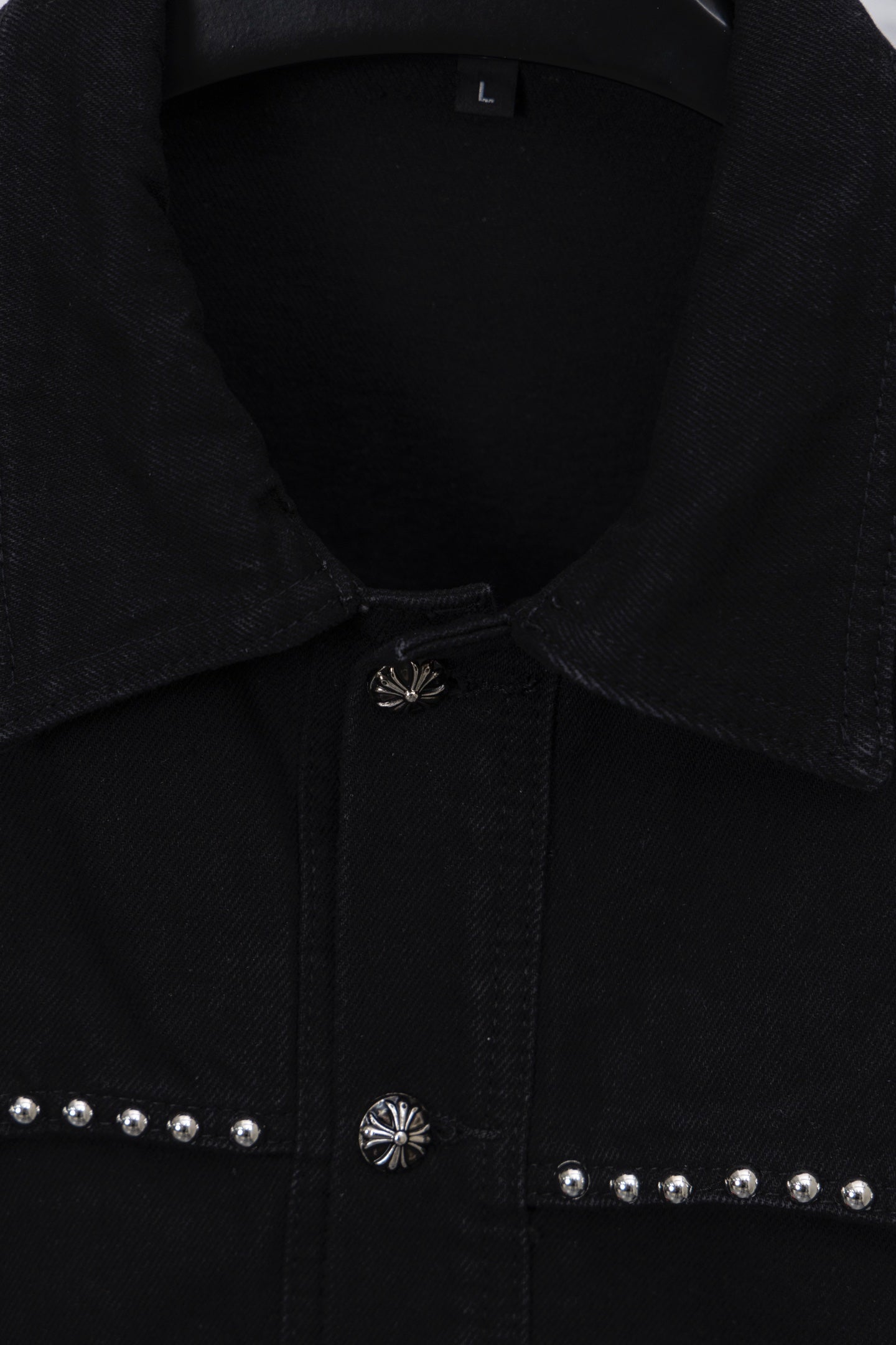 Black button-up collar detail with center placket emblem and stud accents