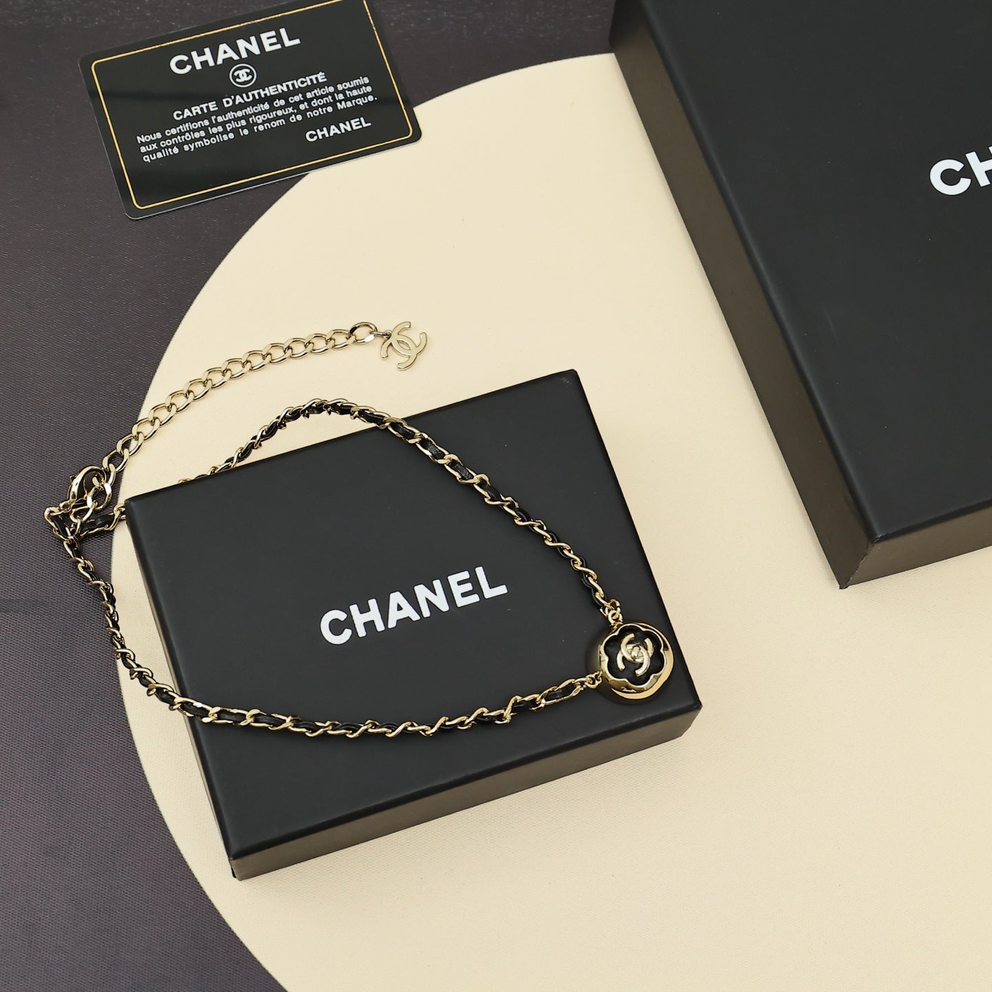 Gold chain necklace with small CC emblem and round pendant at center