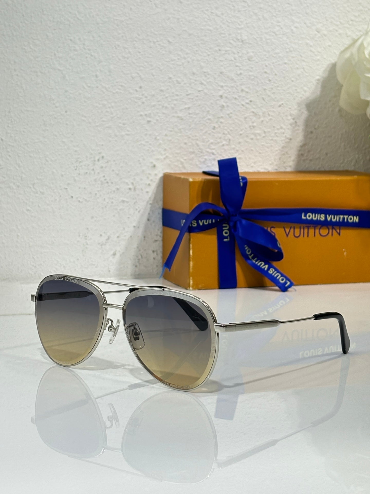 Louis Vuitton sunglasses with silver frames and dark gradient lenses, black temple tips.