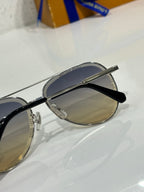 Sunglasses with silver frame and dark gradient lens, black temple and lens branding visible.