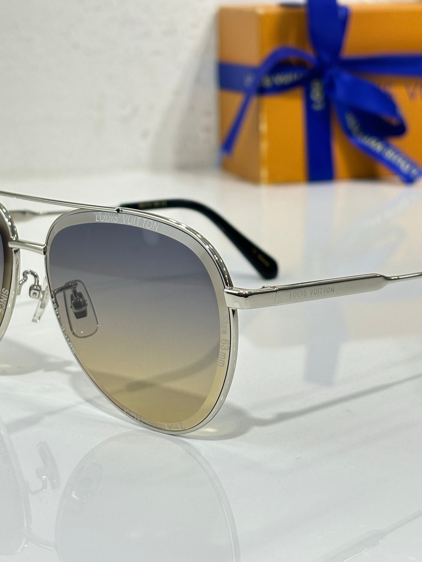 Sunglasses with silver frames, dark gradient lens, and black temple tips, angled side view.