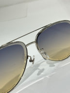 Sunglasses with silver frame and dark-to-light gradient lens, close side angle.