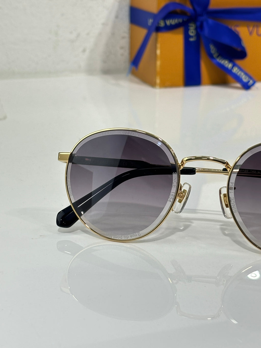 Gold-tone round sunglasses with dark lenses and black temple tips