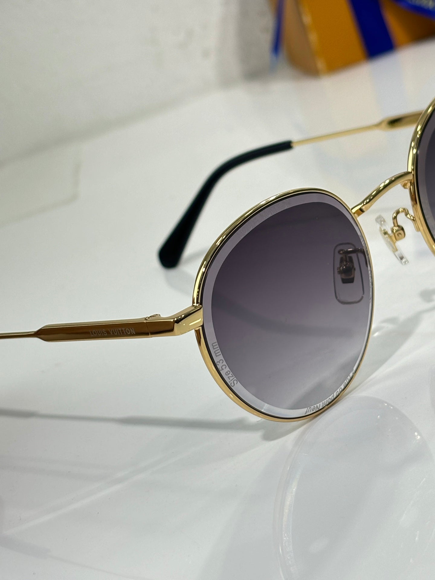 Gold-tone round sunglasses with dark lens and black temple arm detail