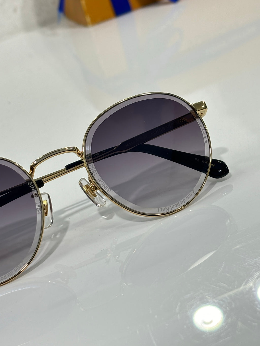 Gold-tone round sunglasses side view with dark lenses and black temple