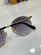 Gold-tone round sunglasses angled side view with dark lenses and black arm