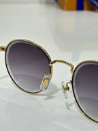 Gold-tone round sunglasses hinge detail with dark lenses and metal frame