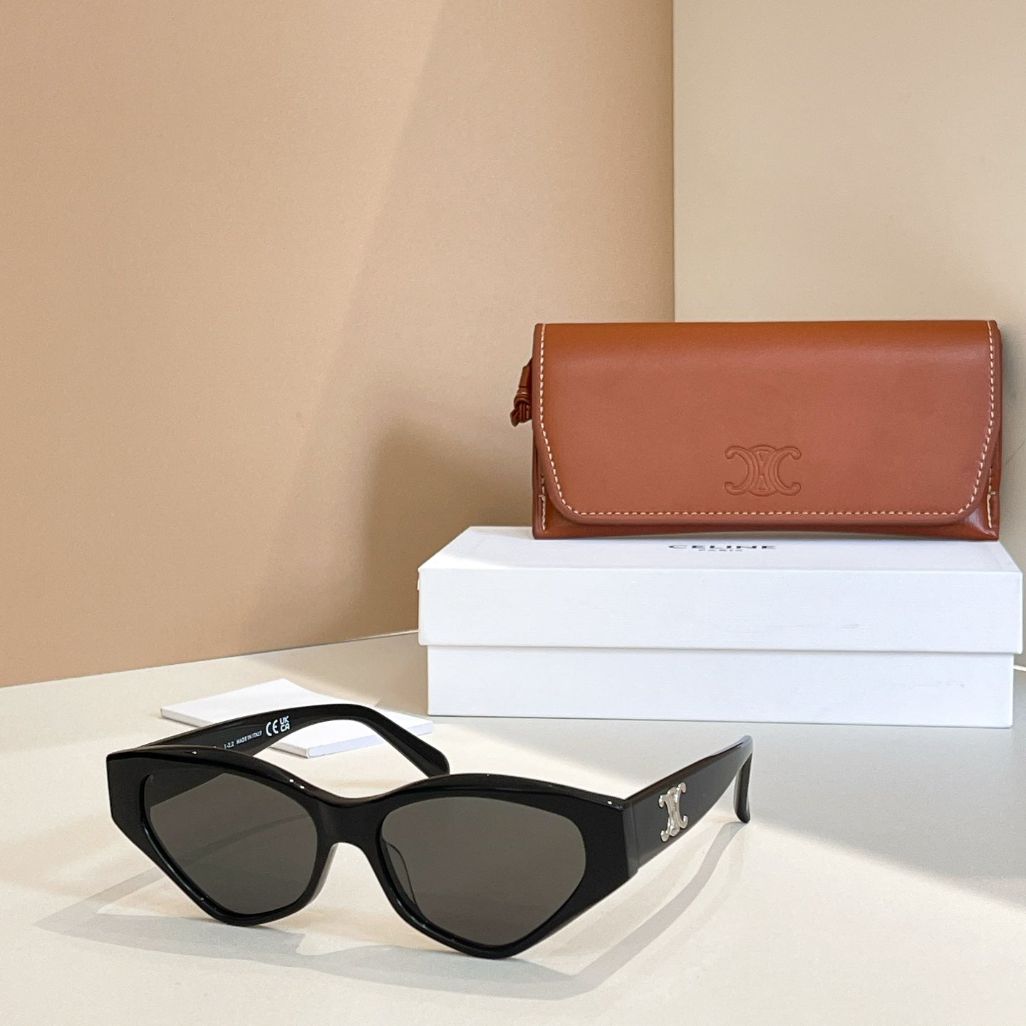 Black cat-eye sunglasses with dark lenses and gold logo on temples