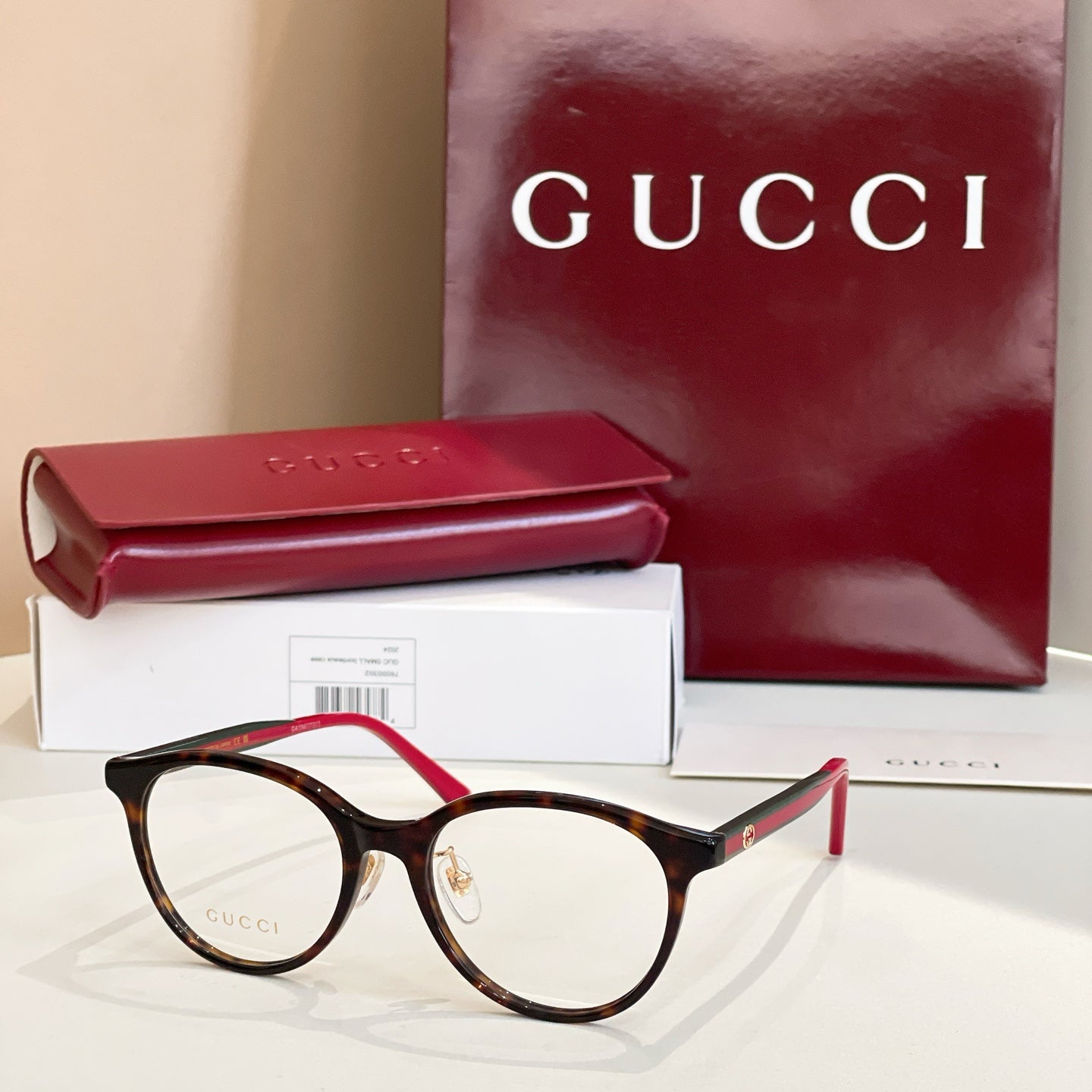 Gucci eyeglasses with dark frames and red temple tips, round clear lenses
