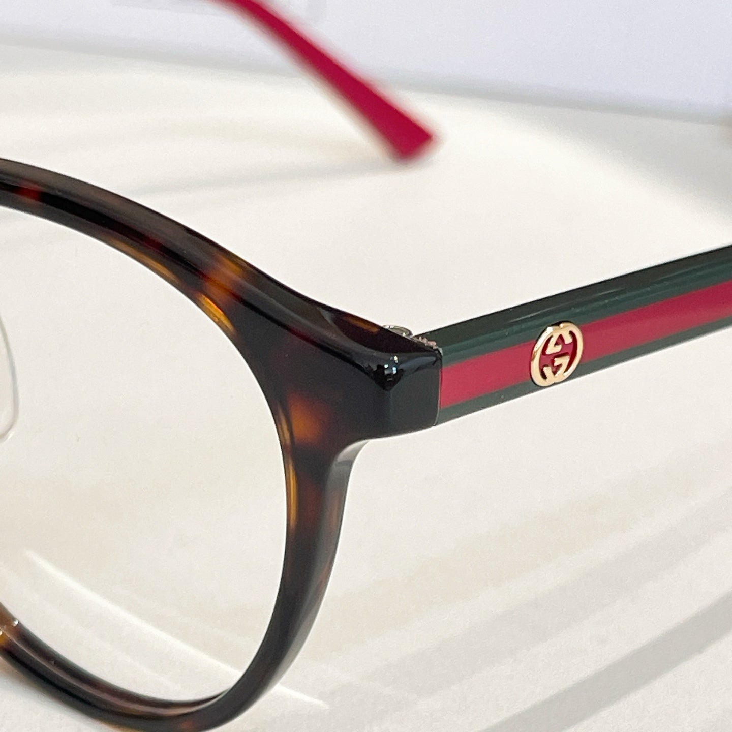 Gucci eyeglasses close-up: dark frame with red temple and green stripe detail