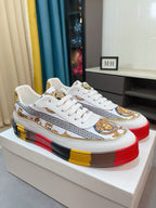 Versace luxury sneakers pair, white uppers with Greek border and gold crest accents.