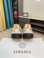 Versace luxury sneakers heel view: white with gold crest, dark rubber heel blocks.