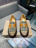 Brown leather loafer pair with tan plaid panels and gold buckle closure, front view