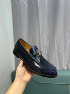Burberry navy patent leather loafer held in hand, TB buckle detail