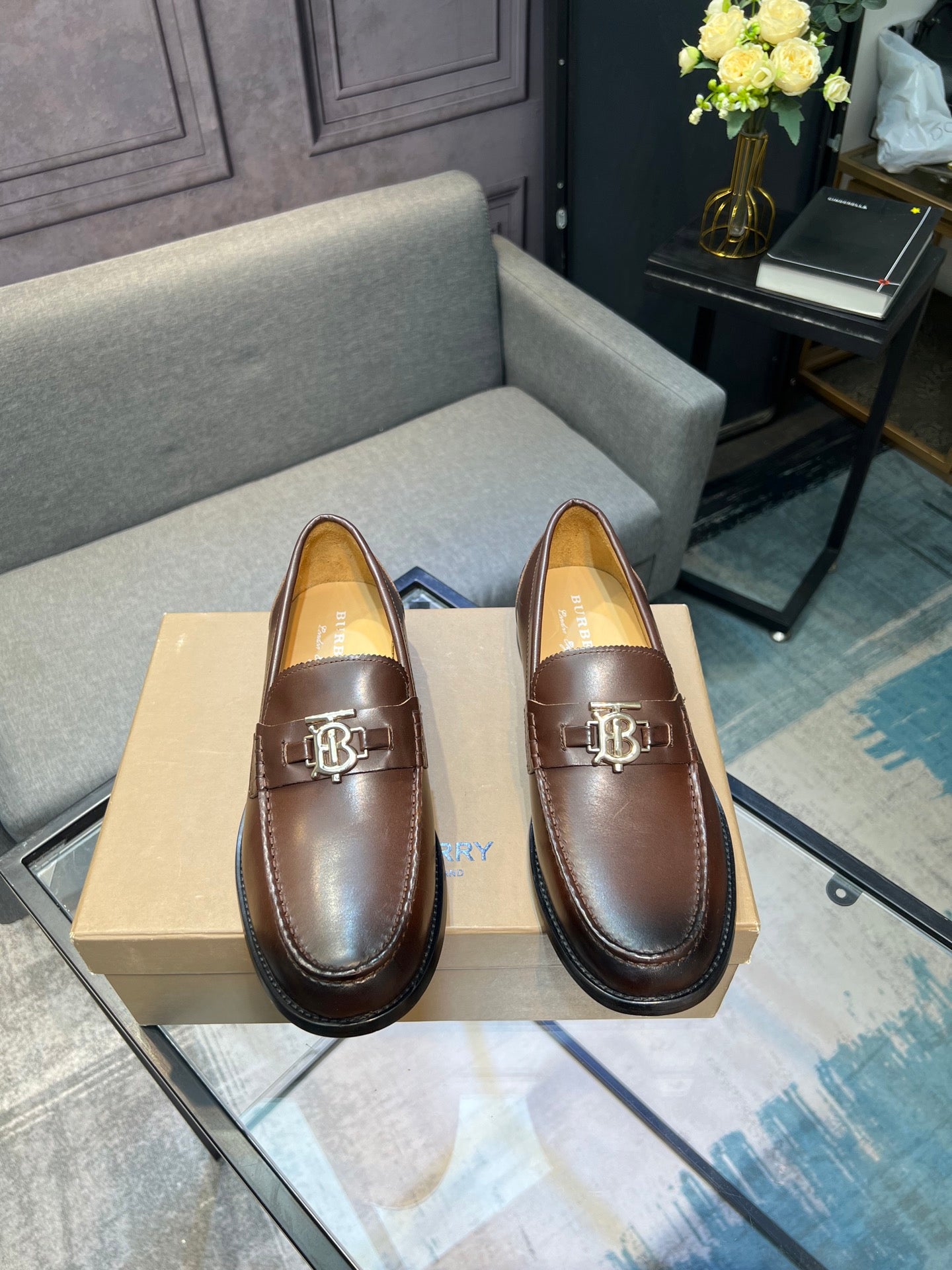 Brown leather loafer pair with metal TB buckle and smooth finish