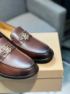Close-up of brown leather loafer with metal TB buckle and stitched trim