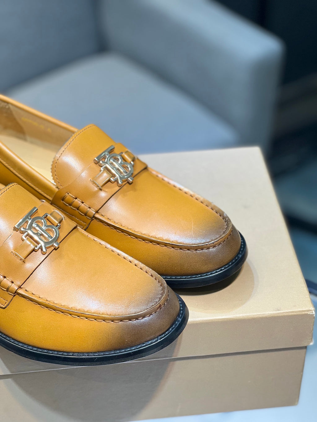 Burberry tan leather loafers close-up, TB metal bit on front strap