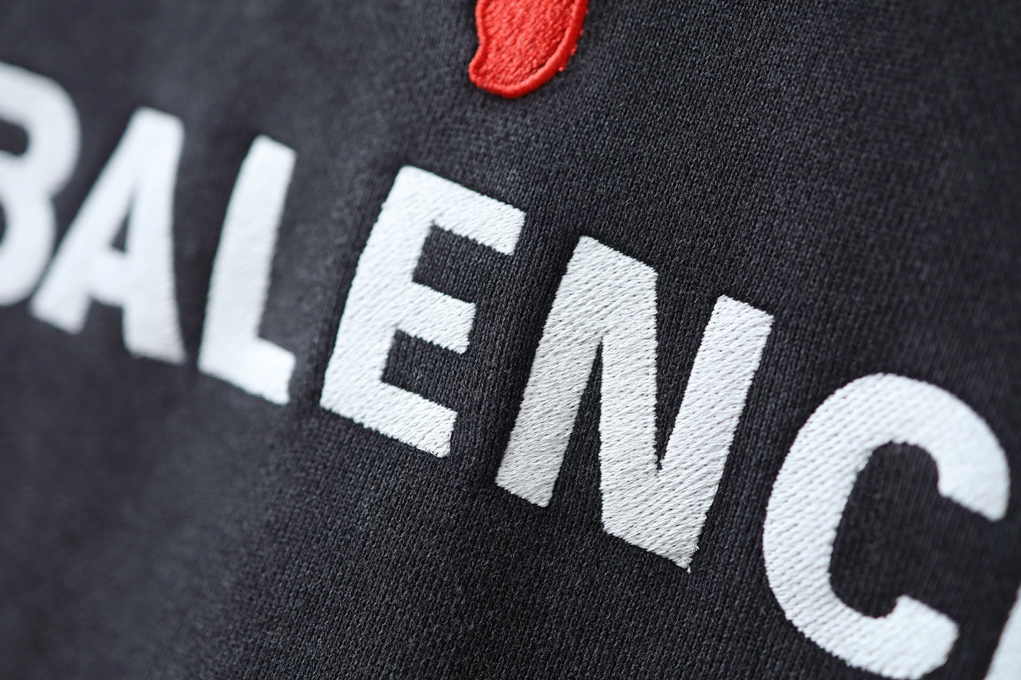 Charcoal gray hoodie fabric closeup with BALENCIAGA lettering and red puma logo