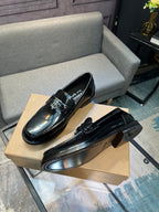 Black leather loafer shoes, angled view with metal buckle and low heel