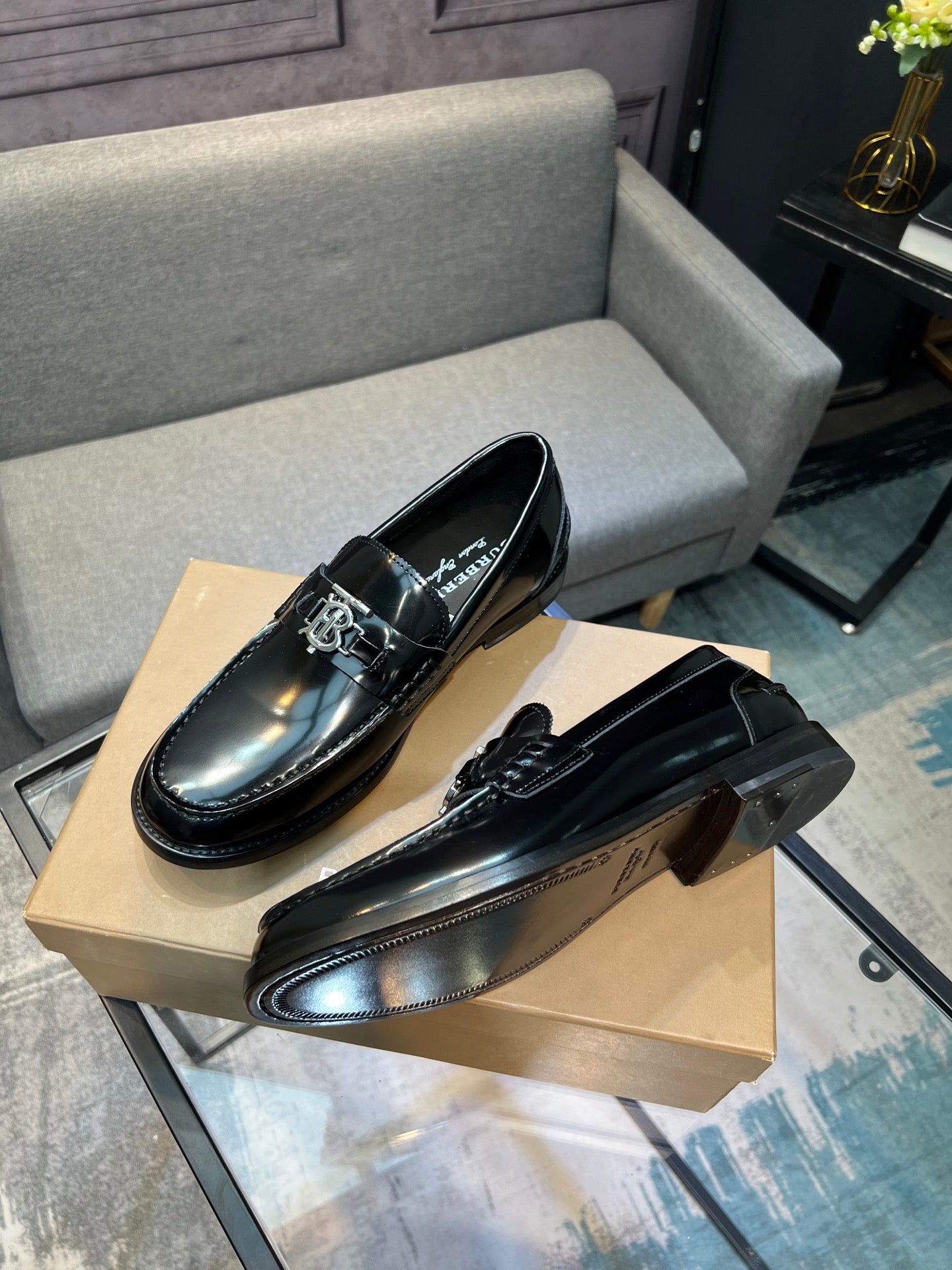 Black leather loafer shoes, angled view with metal buckle and low heel