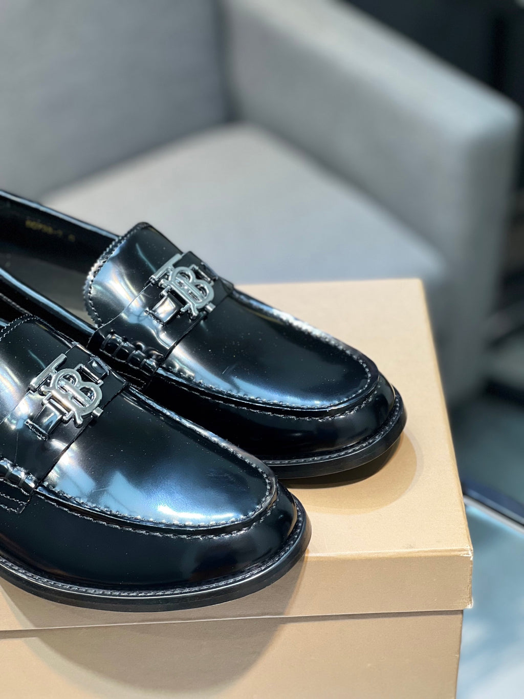 Black leather loafers close-up, silver metal bit detail on glossy finish