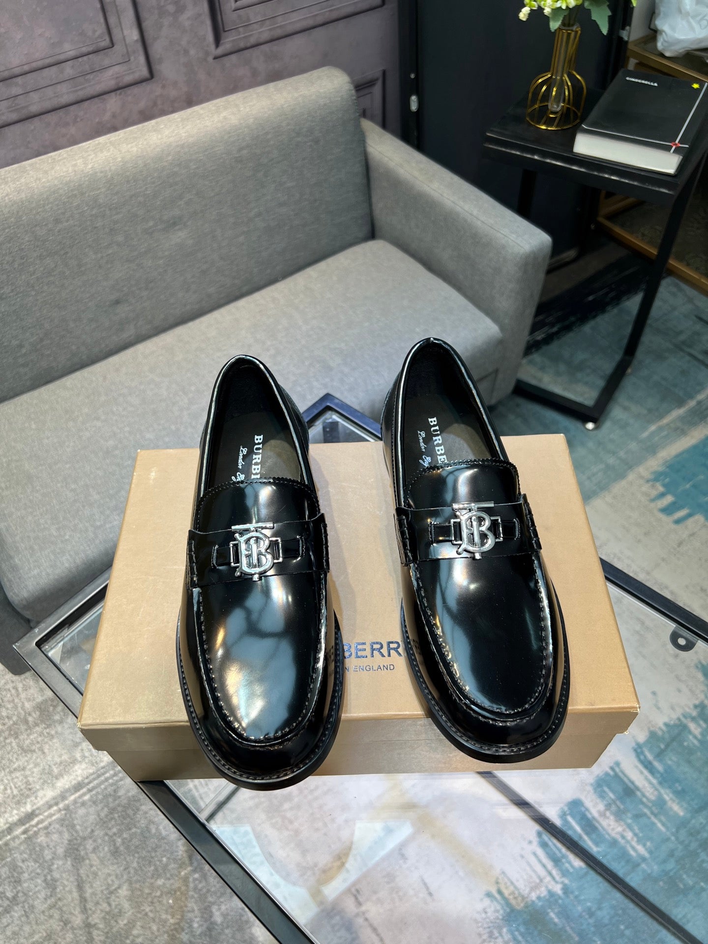 Black leather loafer shoes, front view with metal buckle ornament and stitching
