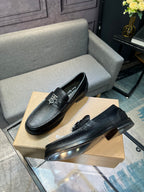 Burberry logo loafers, dark leather slip-ons with metal emblem, angled view