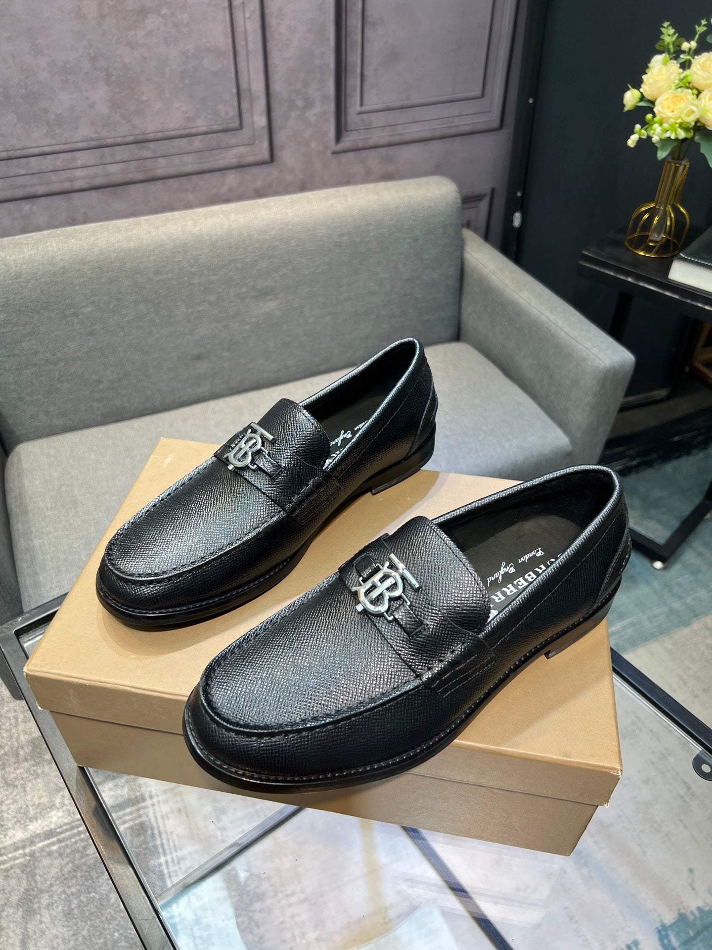 Burberry logo loafers, dark textured leather with metal emblem on vamp, side view