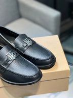 Burberry logo loafers close-up, dark leather texture with metal emblem on the vamp