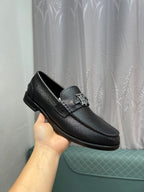 Burberry logo loafer in dark leather, held in hand with metal emblem on the vamp