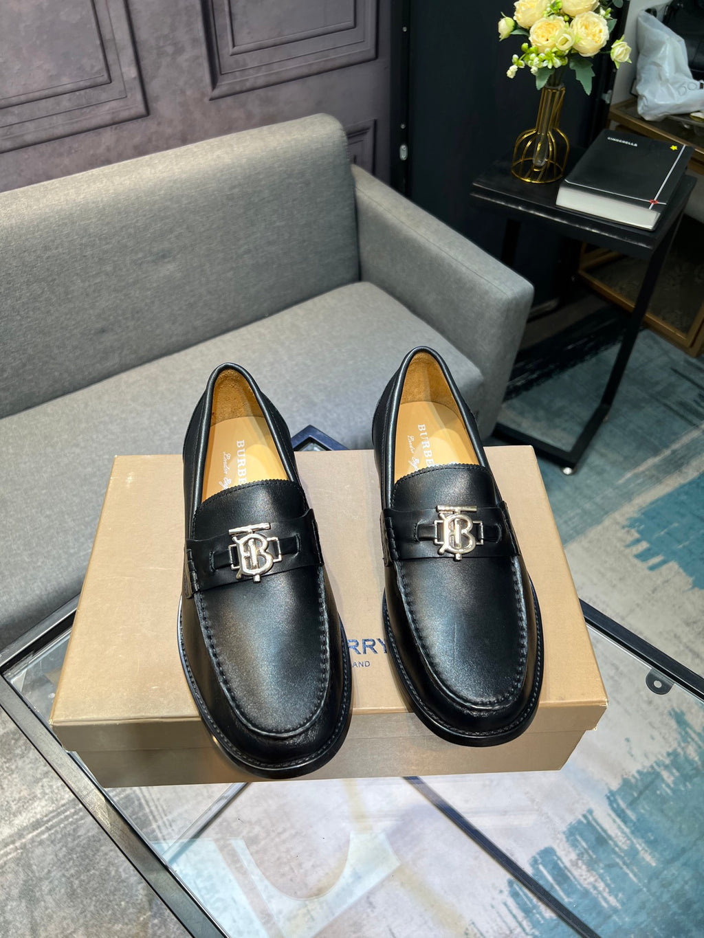 Burberry dark leather loafer pair with metal buckle, front view on box