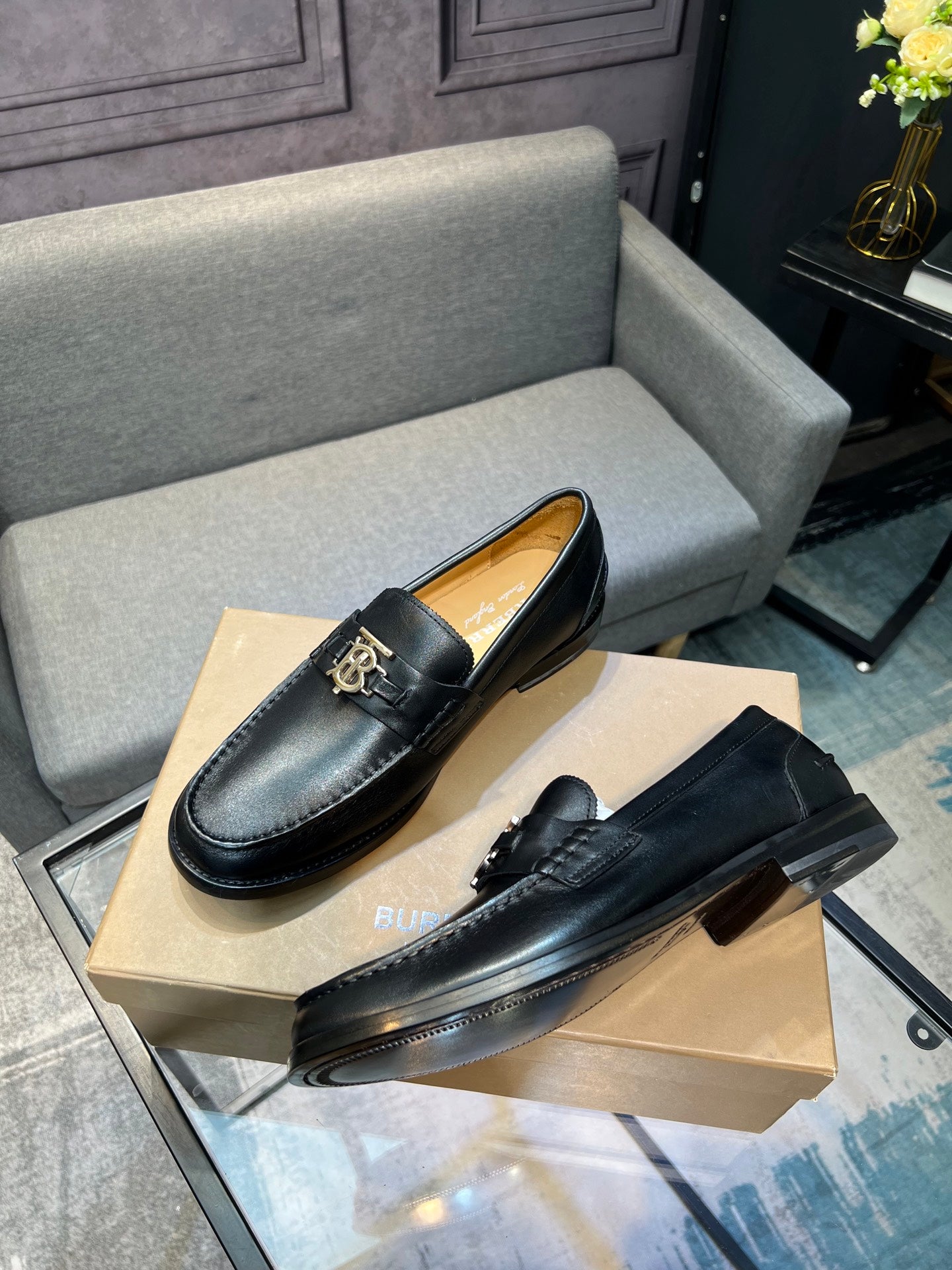Burberry dark leather loafer pair with metal buckle detail, angled on box