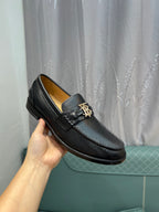 Burberry dark leather loafer with metal buckle, held in hand