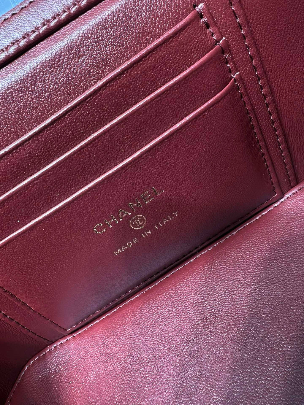 Dark red leather bag interior card holder with CHANEL and MADE IN ITALY embossed.