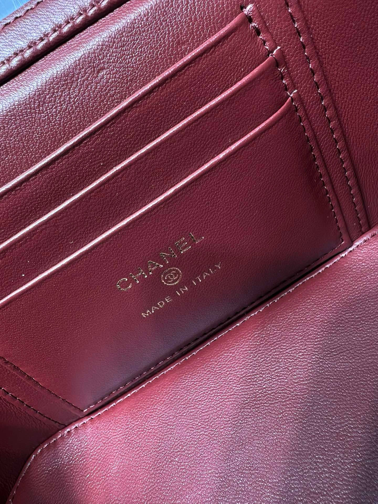 Dark red leather bag interior card holder with CHANEL and MADE IN ITALY embossed.