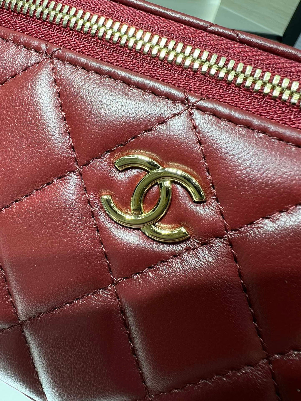Quilted dark red leather flap with gold-tone CC emblem and stitch detailing.
