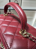 Dark red quilted bag with rounded top handle and gold-tone hardware.