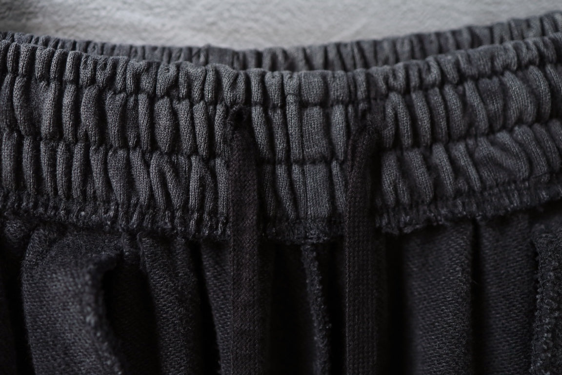 Balenciaga elastic waistband with gathered pleats on dark pants.