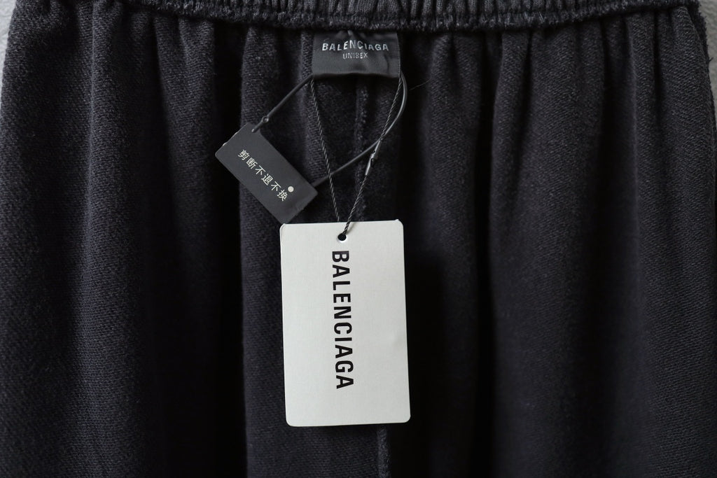 Balenciaga pants with hang tag near elastic waistband, dark fabric.